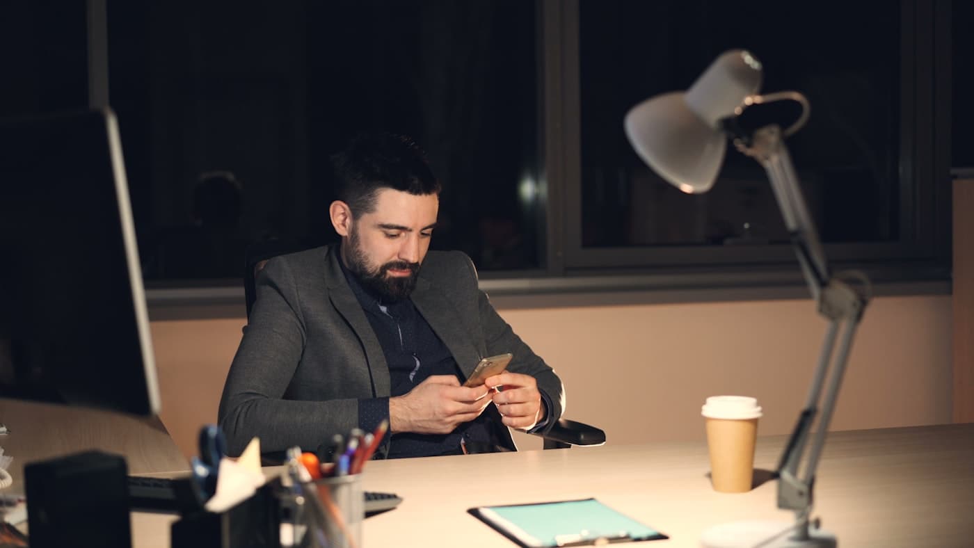 Profissional respondendo mensagens pelo celular tarde da noite no escritório